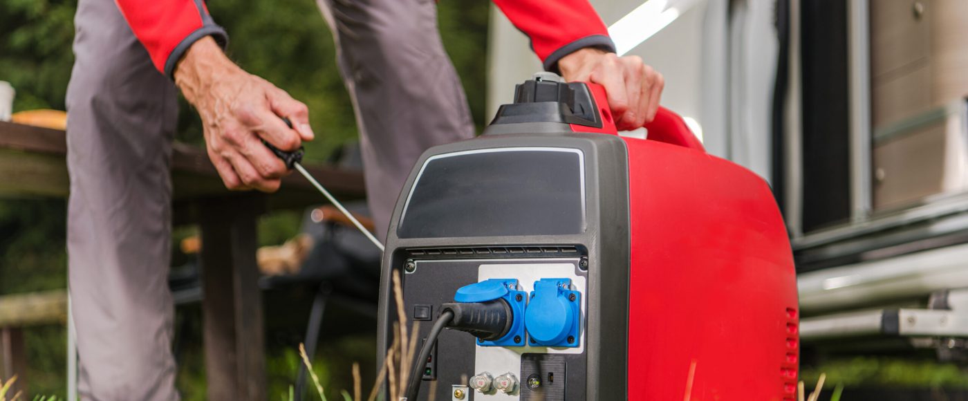 Caucasian Men in His 40s Firing Up Gas Powered Portable Inverter Generator To Connect Electricity To His Camper Van.